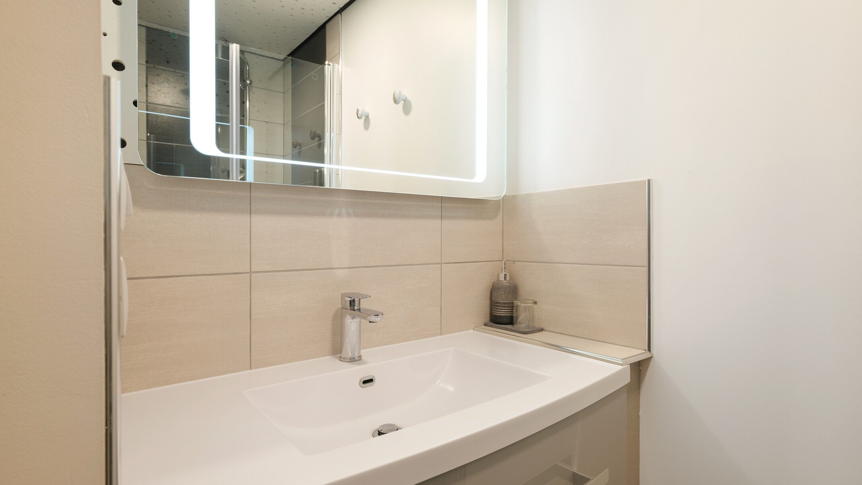 A bathroom with a white sink, a mirror, and a shower enclosure.