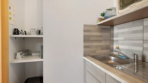 A kitchen with a stainless steel sink, a microwave, and a tiled backsplash.