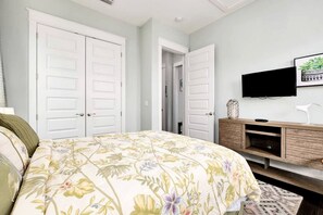 Ein Schlafzimmer mit floralem Bettbezug, einem an der Wand montierten Fernseher und einer Holzkammer.