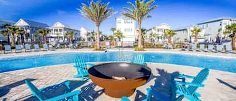 Zona de piscina con sillones de descanso, una mesa y vistas despejadas de los edificios circundantes.