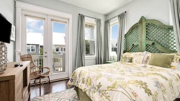 A bedroom with a bed, a desk, a chair, and a view of the outside.