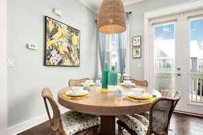 Un coin repas avec une table ronde en bois, des chaises en osier et un luminaire suspendu.