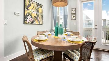 Un coin repas avec une table ronde en bois, des chaises en osier et un luminaire suspendu.