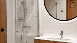 A bathroom with a glass-enclosed shower, a wooden vanity with a sink, and a mirror. - Cobalt36 (Bolesławiec)