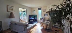 A living room with a sofa, a chair, a TV, and a plant. - Beautiful, Spacious Single-Story House with a Large Enclosed Garden in Trégunc (Trégunc)