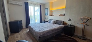A bedroom with a bed, bedside tables, a desk, a chair, a standing lamp, and a wall-mounted shelf. - Beautiful, Spacious Single-Story House with a Large Enclosed Garden in Trégunc (Trégunc)