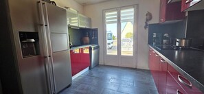 A kitchen with a refrigerator, a sink, and a window. - Beautiful, Spacious Single-Story House with a Large Enclosed Garden in Trégunc (Trégunc)