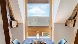 A dining table with a tray of glasses and a bottle, two chairs, and a window with a view of the sky. - Guest Room “Le clair de Lune” with Shared Terrace & Garden, Wi-Fi (Romillé)