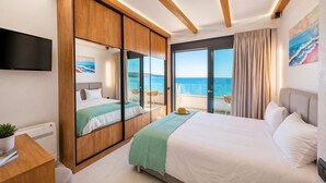 Een hotelkamer met een groot bed, een televisie, een bureau en uitzicht op zee.