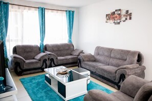 Ein Wohnzimmer mit drei Sofas, einem Couchtisch und einem Wandbild.