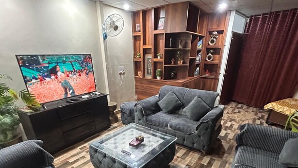Una sala de estar con televisor, sofás, una mesa de centro y una estantería de madera.
