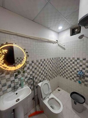 Un baño con lavamanos, inodoro y espejo con luz.