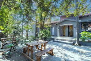 A patio with wooden tables and benches, surrounded by trees and potted plants. - Boutique Hotel-Style 4Bed Home In Fernda (Randburg)