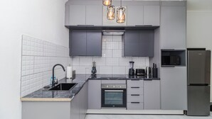 Eine moderne Küche mit grauen Schränken, einem eingebauten Backofen, einer Mikrowelle und einem Edelstahl-Kühlschrank.