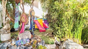 A garden with a stone statue, colorful hats, and a slide. - Bicorna Chania Pool Escape - Yellow Room 1 (Plaka)