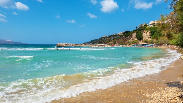 A coastal beach with clear turquoise waters, a rocky shoreline, and a building on a hill. - Bicorna Chania Pool Escape - Yellow Room 1 (Plaka)