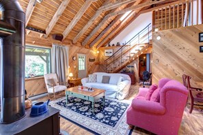A cozy interior with a wooden ceiling, a sofa, a pink chair, a coffee table, and a fireplace. - Warm & Inviting Cabin Retreat Perfect for Year-Round Escapes in Denver, New York (Denver)