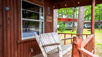 A cabin with a porch, a swing, and a number '5' sign.