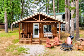 Eine Holzhütte mit Veranda, Sitzbereich und Grill.