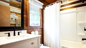 Une salle de bain avec un intérieur en bois, un lavabo blanc, des toilettes et un espace douche.