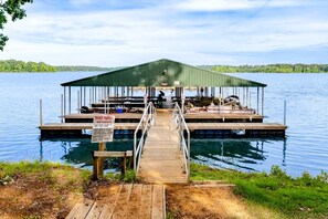 Un muelle con un cobertizo para barcos, un letrero que indica propiedad privada, y una vista despejada del lago.