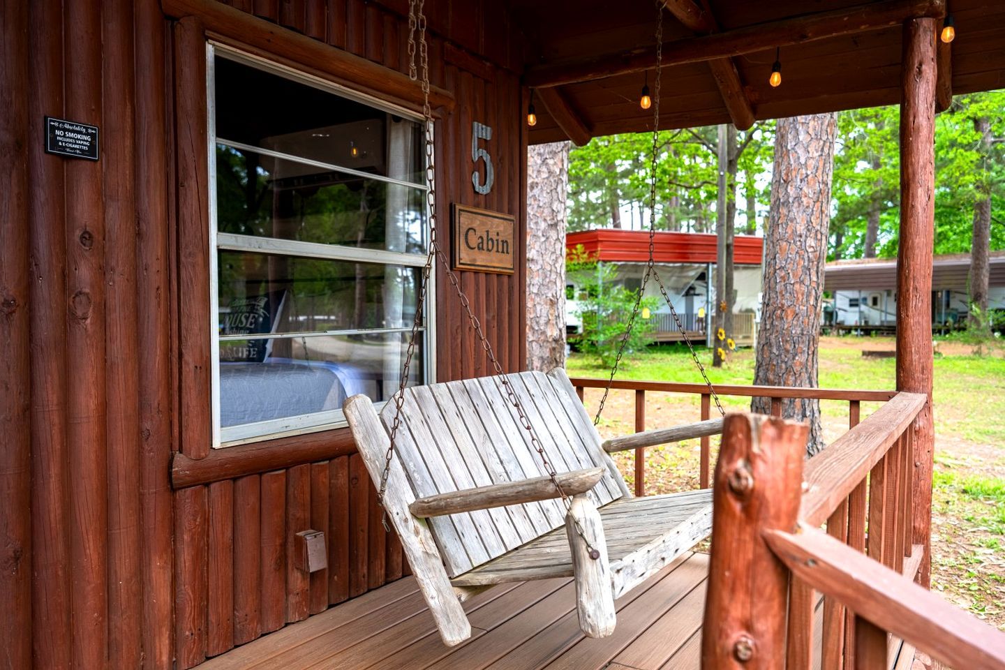 Une cabane avec une véranda, une balançoire et une pancarte portant le chiffre « 5 ».