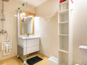 A bathroom with a shower, a sink, a mirror, and a toilet. - Family apartment with a balcony and a view of the mountains (Chamrousse)