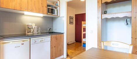 A compact kitchen with a dishwasher, coffee maker, and wooden cabinets.