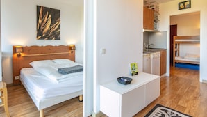 Une chambre à coucher avec un lit en bois, des lampes de chevet, un tableau et une petite table de chevet blanche sur laquelle se trouve un panier.