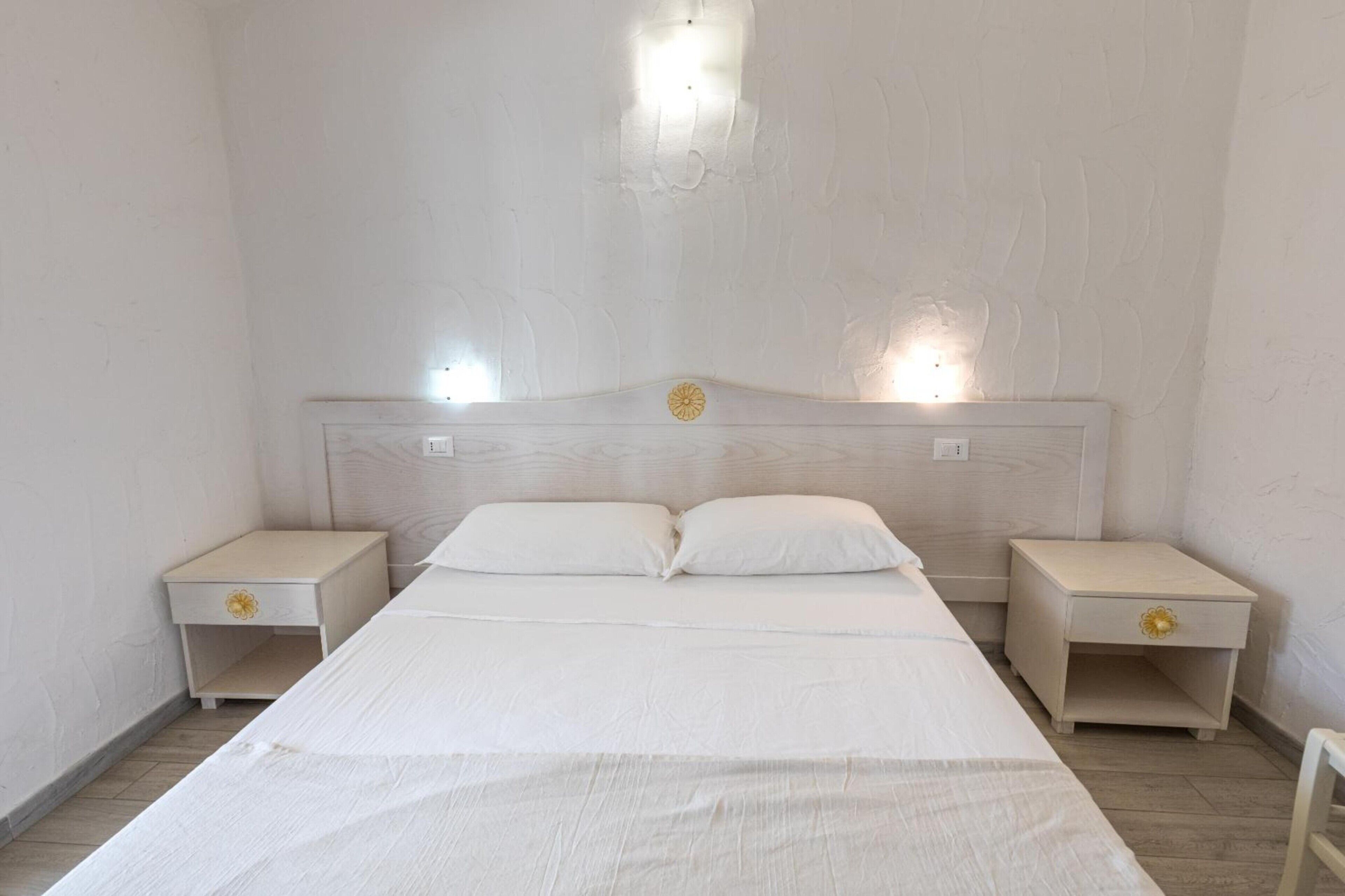A bedroom with a single bed, two bedside tables, and a headboard with a light fixture.