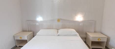 A bedroom with a single bed, two bedside tables, and a headboard with a light fixture.