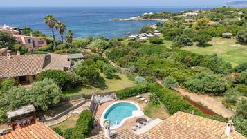 A residential property with a swimming pool, terracotta roof tiles, and a view of the sea.