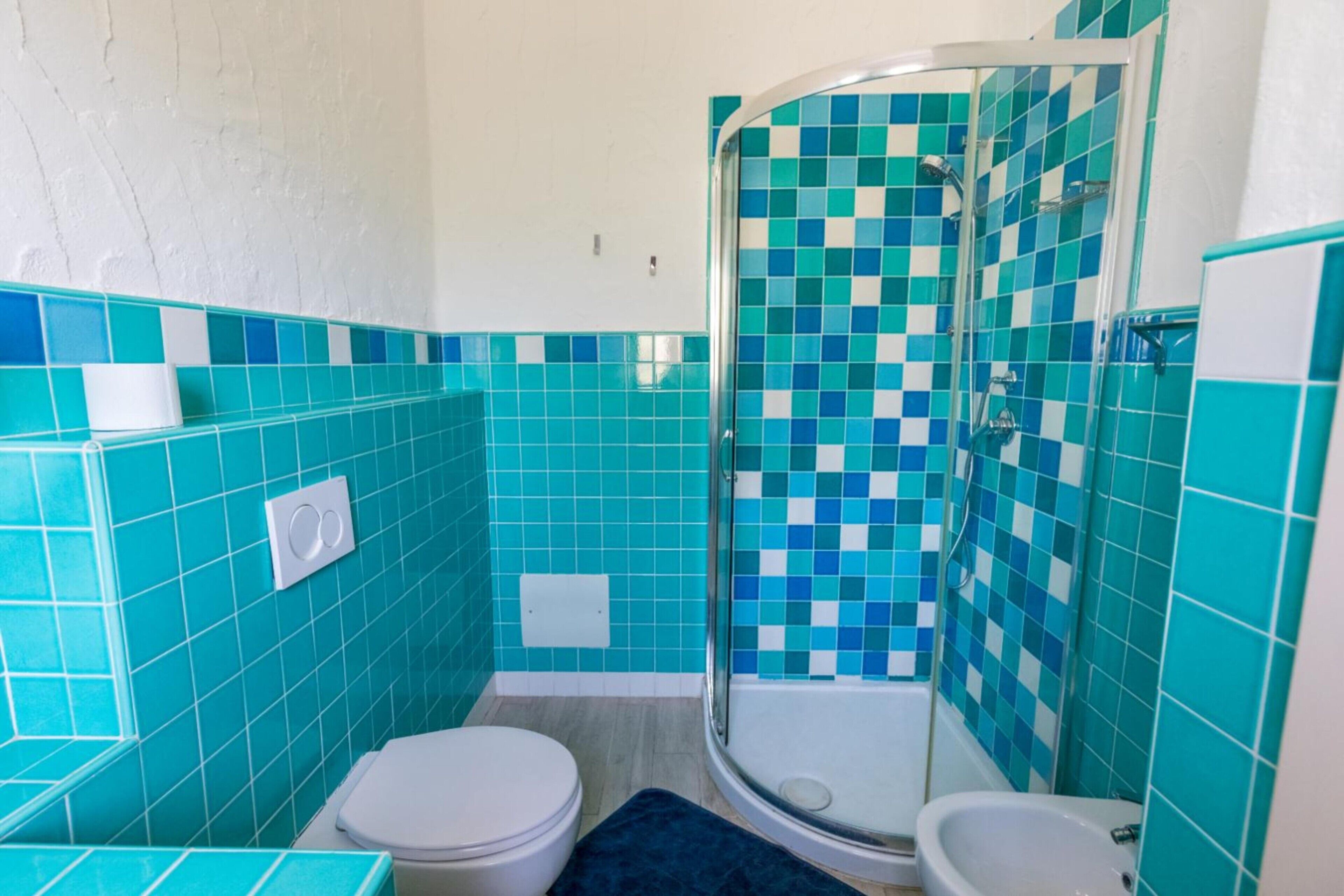 Ein Badezimmer mit Dusche, Toilette und Bidet, mit blau-weißen Karokacheln.