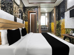 Ein Hotelzimmer mit einem großen Bett, einem Holzkopfteil, einem Flachbildfernseher und Blick auf einen Balkon.