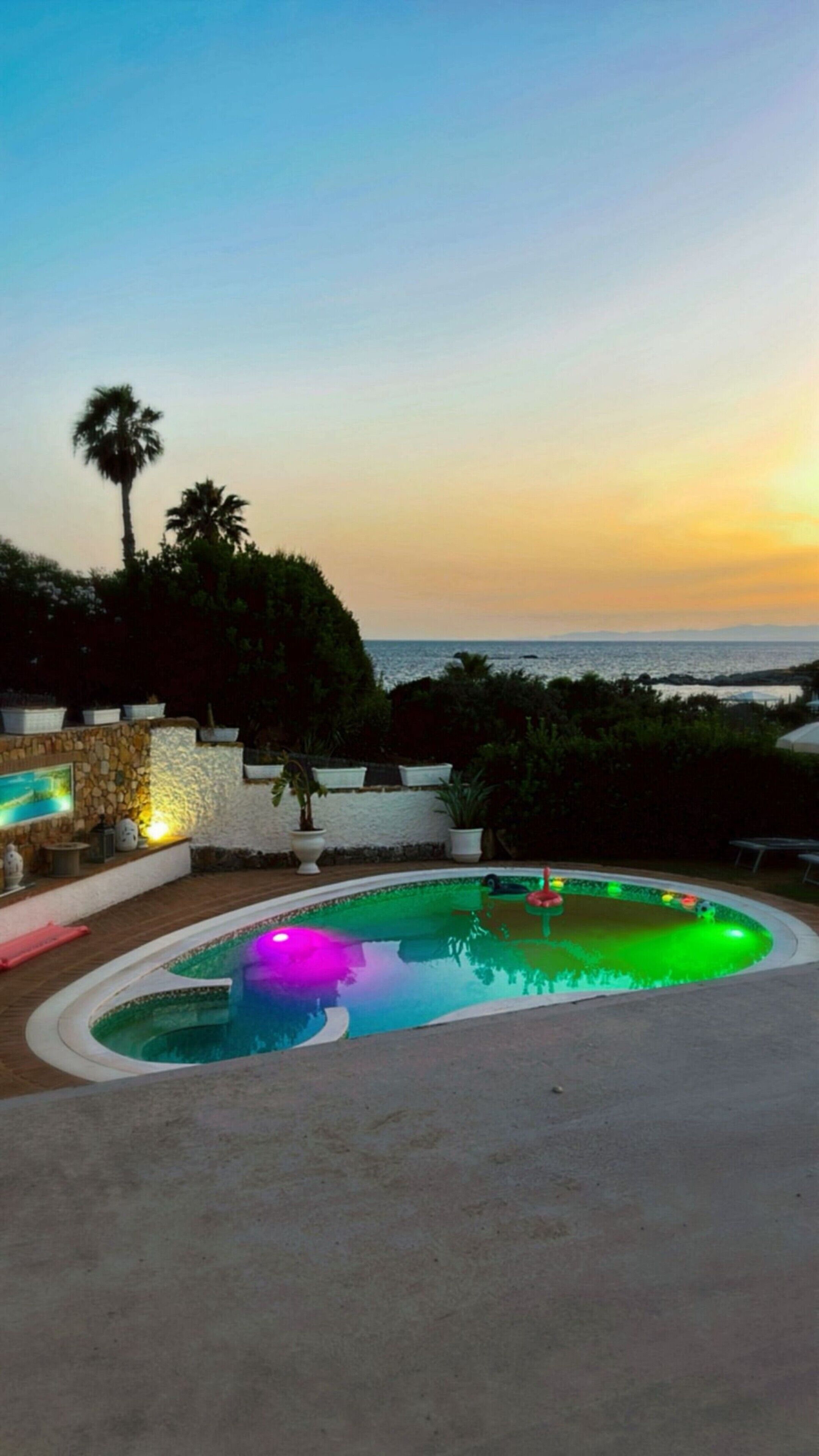 Una piscina con vistas al mar al atardecer.