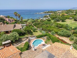 A residential property with a swimming pool, terracotta roof tiles, and a view of the sea.