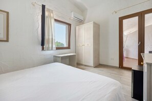 Un dormitorio con cama, escritorio, armario y aire acondicionado.
