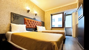 Quarto de hotel com duas camas, uma janela grande e uma porta que dá para o exterior.