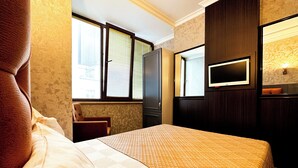 Quarto de hotel com cama, televisão e janela com persianas.