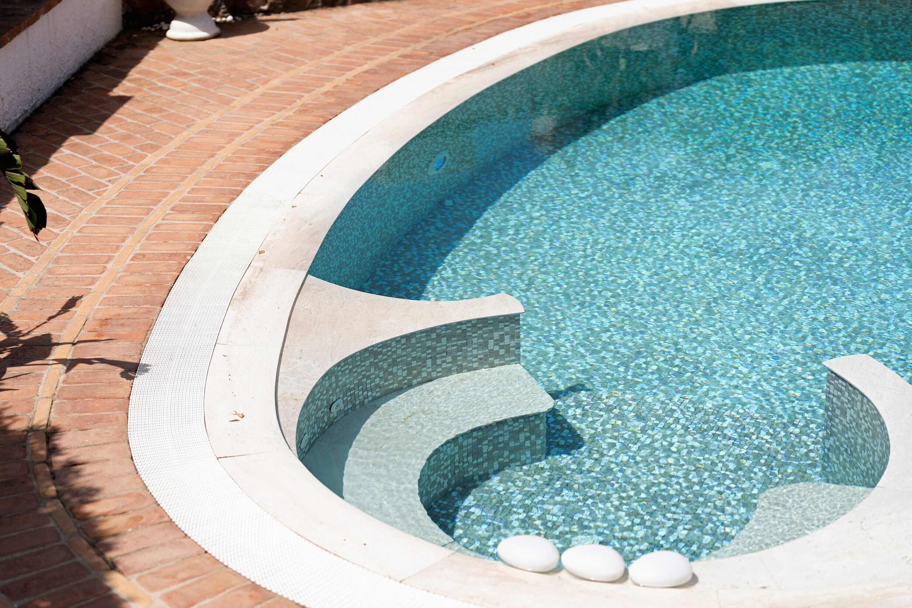 Una piscina con borde de azulejos y fondo de piedras.