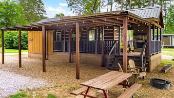 A covered outdoor area with wooden benches and a grill.