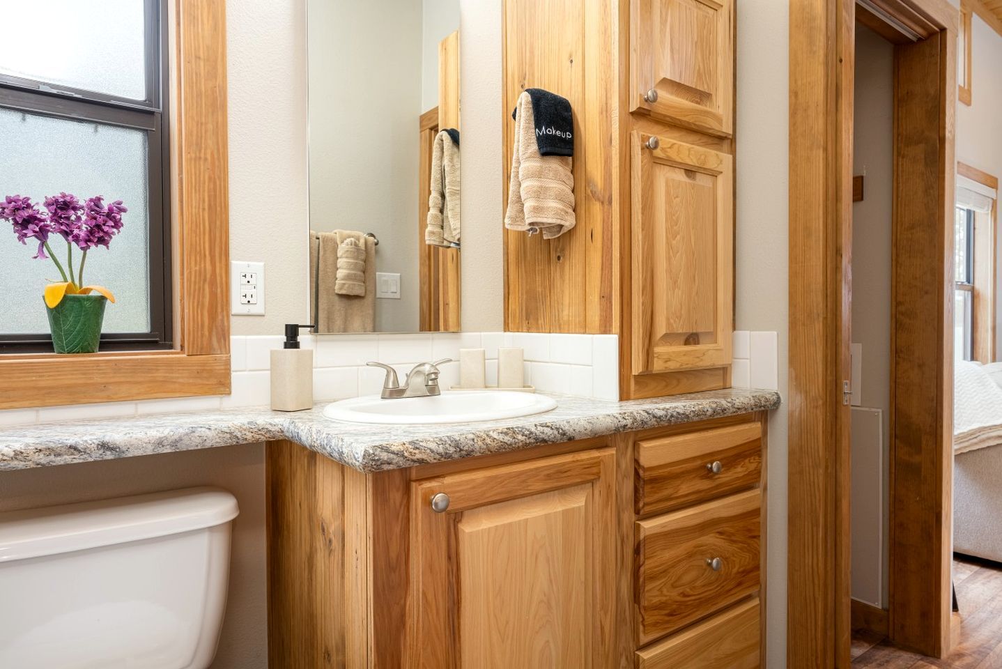 Une salle de bain avec un meuble-lavabo en bois, un évier, un miroir et des serviettes.