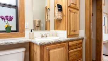 Une salle de bain avec un meuble-lavabo en bois, un évier, un miroir et des serviettes.