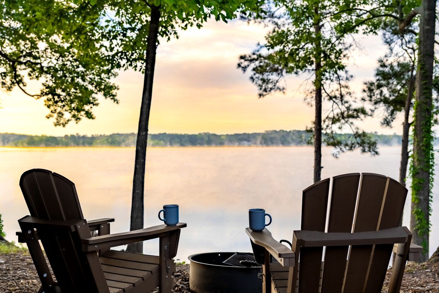Duas cadeiras Adirondack de frente para um lago, com vista para o horizonte.