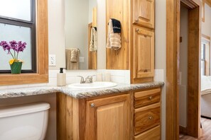 Un baño con tocador de madera, lavamanos, espejo y toallas.