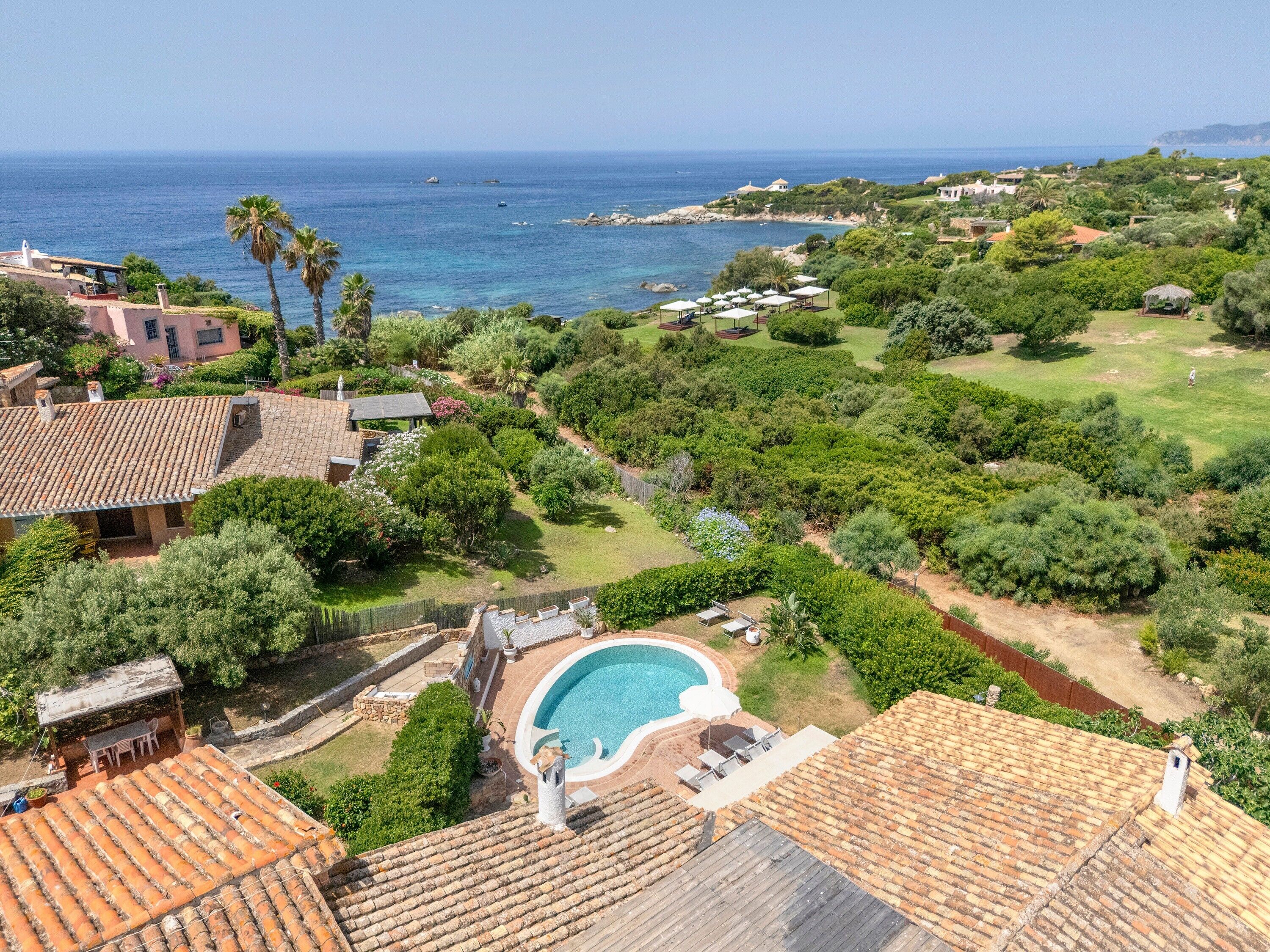 Una propiedad residencial con piscina, tejas de arcilla y vista al mar.