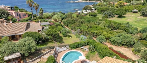A residential property with a swimming pool, terracotta roof tiles, and a view of the sea.