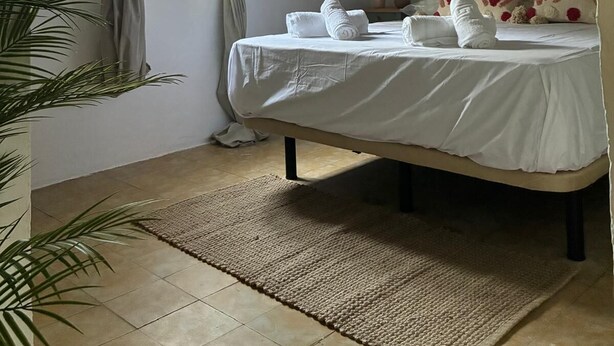 A bedroom with a bed, a window with curtains, a wall-mounted picture, and a woven headboard. - Exclusive three-bedroom home just a few minutes from the beach. (El Puerto de Santa María)
