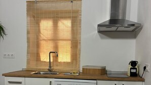 A kitchen with a dishwasher, a window with blinds, a stainless steel range hood, and a patterned floor. - Exclusive three-bedroom home just a few minutes from the beach. (El Puerto de Santa María)