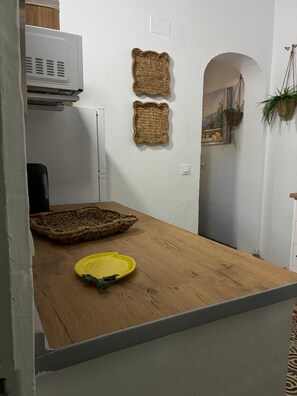 Ein Zimmer mit Holztisch, einer Mikrowelle und zwei Körben an der Wand.
